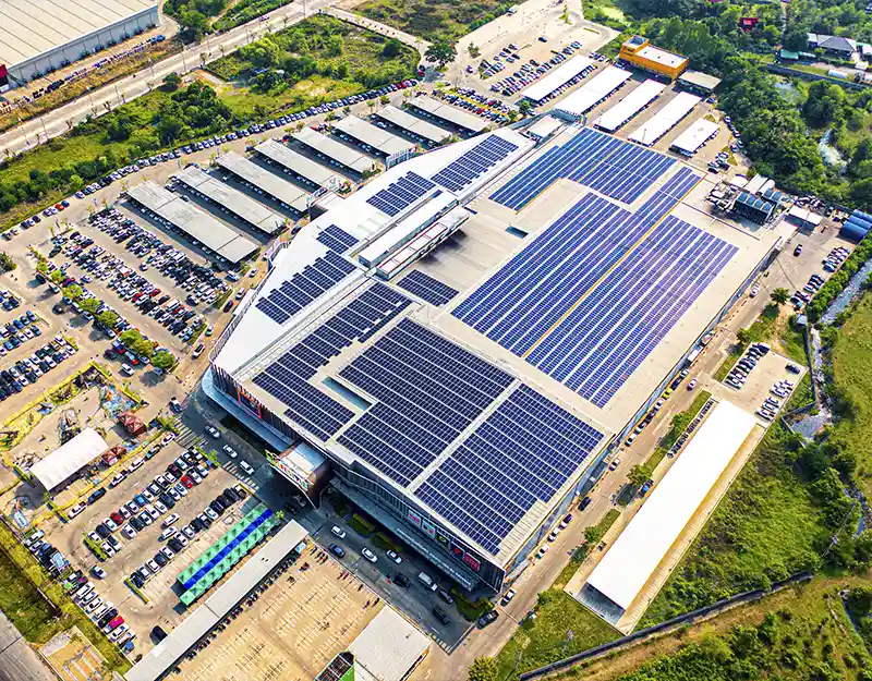 vista de cima de instalação de placas solares da unidade do mercado livre. um galpão localizado em meio a área verde